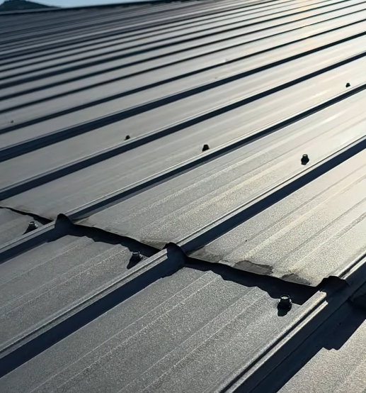 Metal roofing failure due to OSB movement showing warped panels