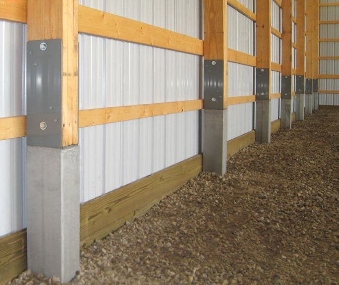 Perma-Column concrete bases with steel brackets installed inside a post-frame building