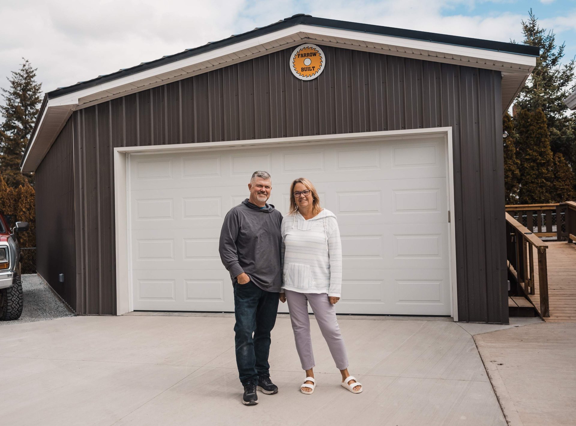 Happy homeowners standing in front of their completed Farrow Built post frame garage