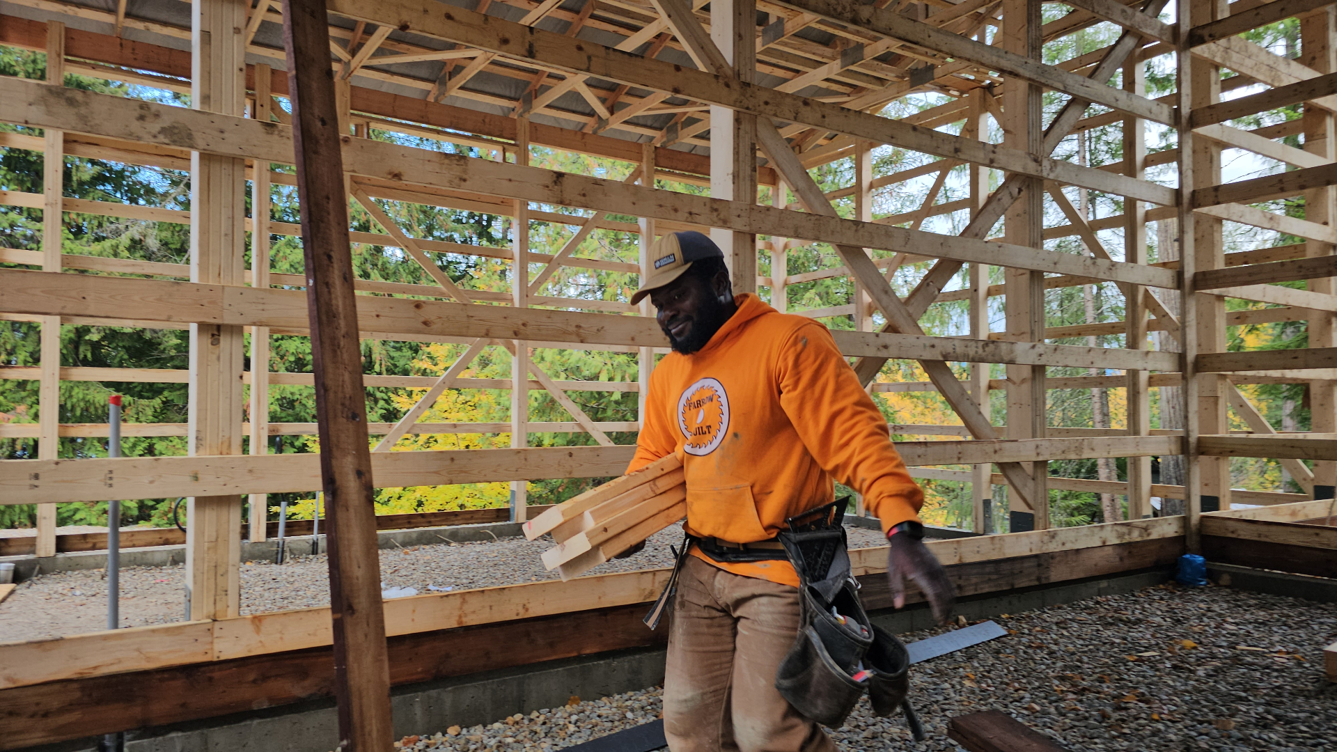 Farrow Built crew member carrying lumber at a post-frame construction site