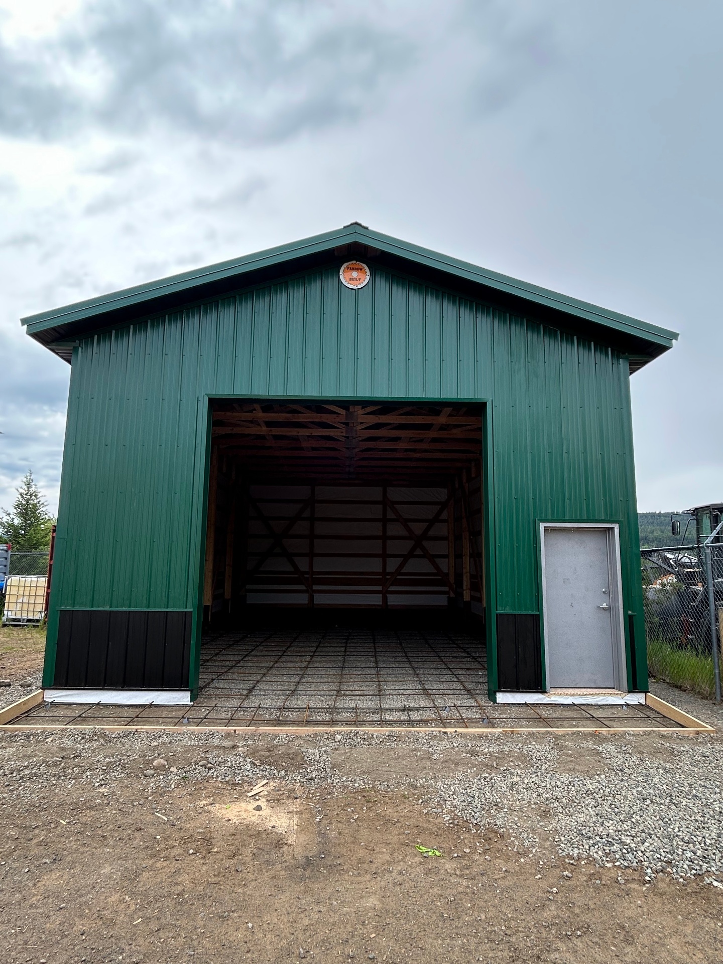 Completed green metal storage shop with open bay door at West Fraser facility